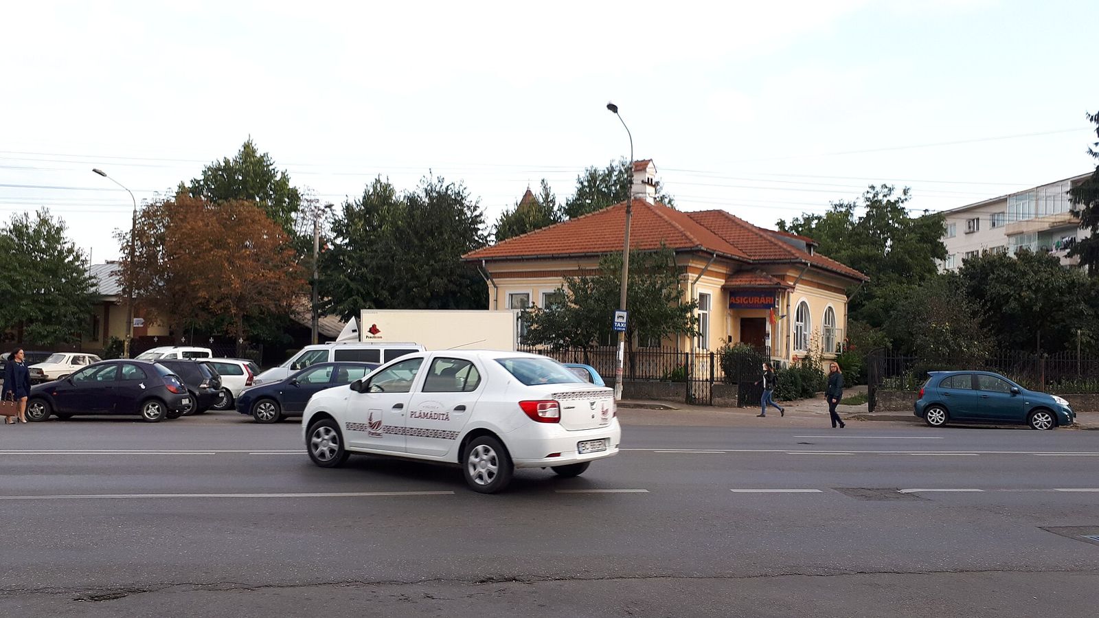Stradă din Bacău cu o casă cu acoperiș de țiglă și mașini parcate